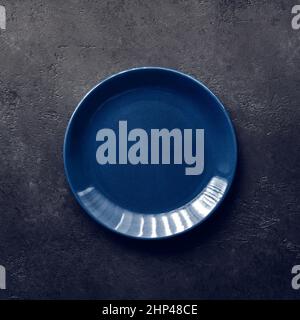 Empty blue plate on black background, vintage toning Stock Photo