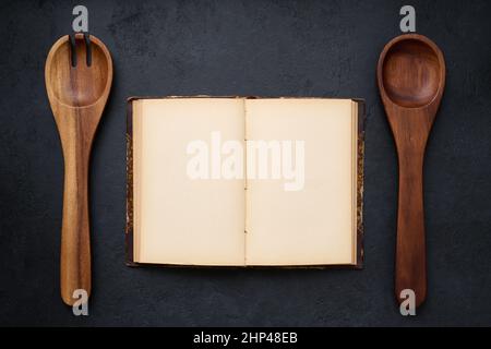 Open antique cookbook with blank pages and two wooden spoons, top view, layout Stock Photo