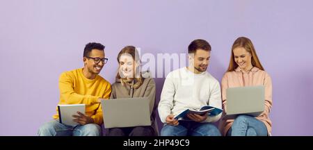 Student friends prepare for lecture together with help of gadgets and notebooks. Stock Photo