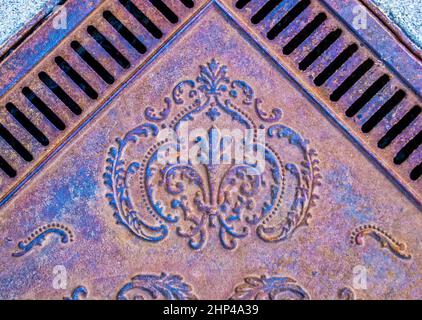 Vintage ornamental metal sidewalk grate - view from above on angle grainy rusted grungy and colorful. Stock Photo