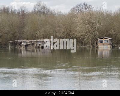 A small old wooden house close to the bank of a river is affected by a huge flood. Stock Photo