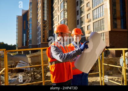 Builder contractor and engineer architect discussing blueprint paper project plan. Construction site Stock Photo