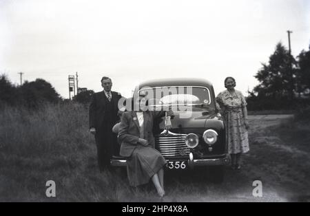 1949, historical, outside on a muddy counry track, a father, mother and daughter posing by their new car, a Singer SM1500, England, UK. A 4-door small family saloon car produced between 1948 to 1956, the SM1500 was made by Singer Motors a British motor vehicle company founded in 1874 in Coventry, England by George Singer. Orginally a maker of bicycles, in 1901 the business started making motor cars. Stock Photo