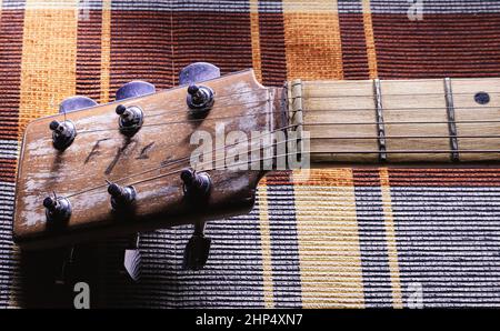 Details of an old vintage style acoustic guitar, view on head with strings, nut and part of a neck. Stock Photo