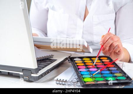 Online learning, hobby classes concept. Girl woman faceless close-up angle learns to paint pictures, draw. Hands with a painting, paints and a brush, Stock Photo