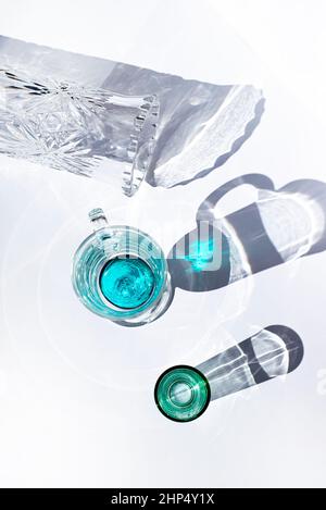 Glass goblets and wine glasses with colored bottoms cast delicate turquoise shadows. Patterned vase. Geometry. Stock Photo