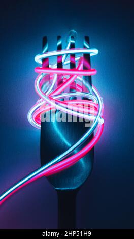 Fork with neon led cable spaghetti on a dark background. Immersive reality concept. Stock Photo