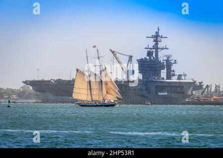 San Diego, USA - October 8, 2017: Replica of the Schooner AMERICA passes the US Navy aircraft carrier USS CARL VINSON (CVN-70) near North Island. Stock Photo