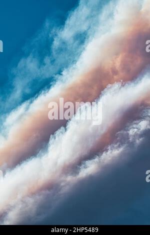 Dynamic wildfire smoke clouds form and stack under clear blue sky Stock Photo