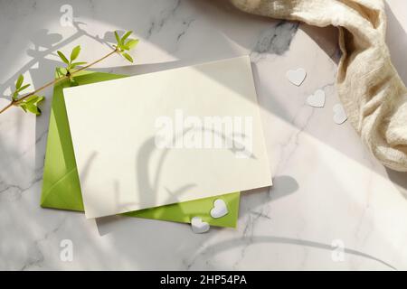 Spring background with blank paper card and green envelope. Fresh leaves, galanthus snowdrop flowers Stock Photo