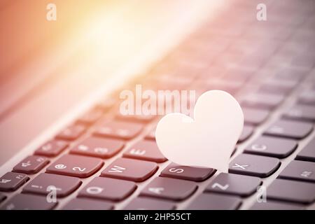 Small white paper heart on computer keyboard. Internet dating concept. Stock Photo