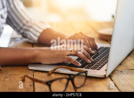 I have some to blog about. Cropped shot of a woman using her laptop on a wooden table. Stock Photo
