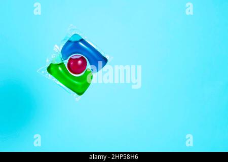 Liquid powder in gel capsule for washing multicolor on blue background Stock Photo