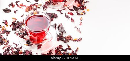 Cup of hibiscus tea (rosella, karkade, red sorrel) on a white background. Hibiscus tea and dry hibiscus petals. Diuretic drink with herbs. Top view. C Stock Photo