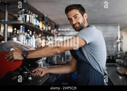 How do you like it. Shot of a young man operating the coffee machine at a cafe. Stock Photo