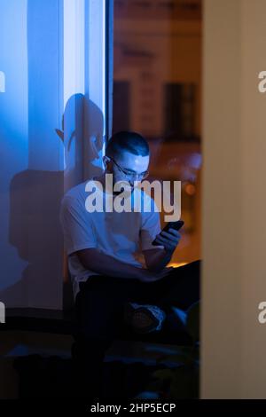 Exhausted businessman rest from work overtime play game on smartphone procrastinating in dark office Stock Photo