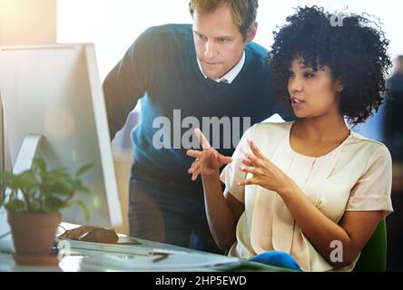 They know design. Shot of two designers talking together while working on a computer in a modern office. Stock Photo
