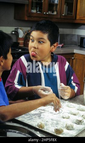 Austin, Texas USA, 1996: Hispanic 10-year-old boy makes a face while baking cookies at home with a friend.  MR ET-315-386  ©Bob Daemmrich Stock Photo