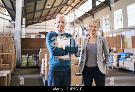 Your shipment left the warehouse today. Portrait of two managers standing in a distribution warehouse. Stock Photo