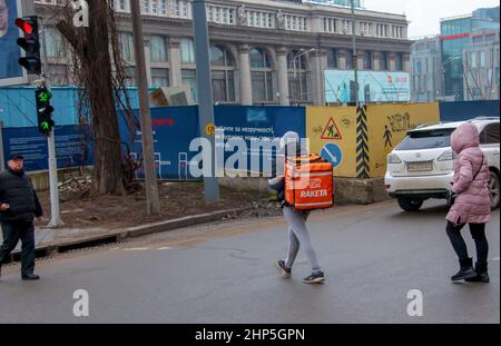 Dnepropetrovsk, Ukraine - 02.10.2022: A delivery service courier with a thermal bag walks through the city. Home food delivery. Stock Photo