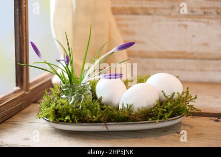 Natural Easter decoration with crocuses and eggs on moss arranged on a plate on a rustic wooden table by the window, copy space, selected focus, narro Stock Photo