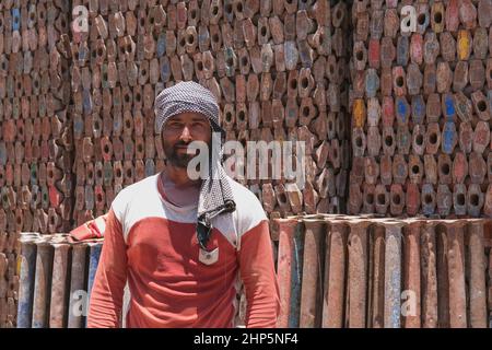Selective focus at face of middle eastern laborer wearing muslim male headdress, working for scrap metal supply warehouse for recycling. Abu Dhabi,UAE Stock Photo