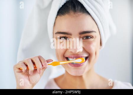 Oral hygiene comes first. Portrait of a beautiful young woman brushing her teeth in the bathroom at home. Stock Photo