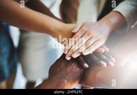 Were all deeply committed to our mission. Cropped shot of a group of businesspeople piling their hands on top of each other. Stock Photo