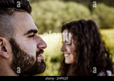 Closeup of a profile view of a smiling bearded man's face in the foreground Stock Photo