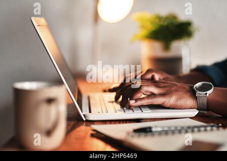 The hard work never ends. Cropped shot of an unrecognizable businessman sitting alone in his home office and working on his laptop. Stock Photo