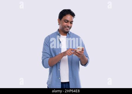 Indian Man Standing Using Phone Isolated. Man Texting on Phone. Technology Stock Photo