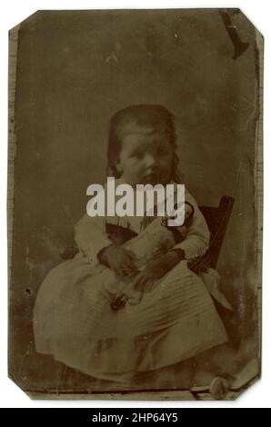 Antique circa 1860 tintype photograph, young girl with her doll. Location unknown, USA. SOURCE: ORIGINAL TINTYPE Stock Photo