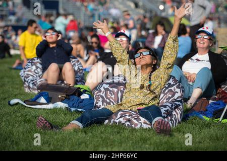 People are seen as they watch a total solar eclipse through protective glasses in Madras, Oregon on Monday, Aug. 21, 2017 Stock Photo
