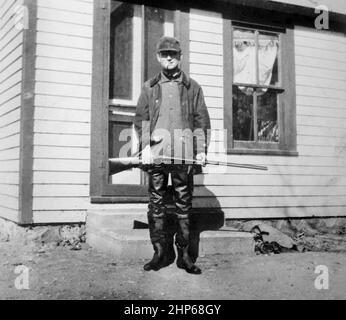 Man wearing waders stands at ready with his shotgun, ca. 1930. Stock Photo