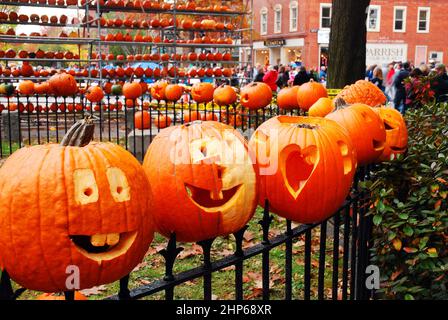 Pumpkins are placed to an iron fence, like heads on a stake, at a pumpkin festival in New England Stock Photo