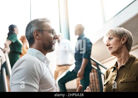 Exchanging some business advice. Shot of two businesspeople talking to each other while standing on a stairwell. Stock Photo