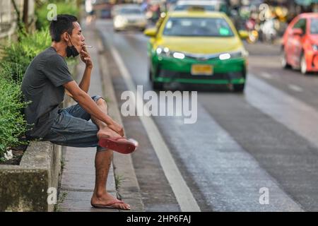 An employee of a market in Bangkok, Thailand, enjoying a moment of rest smoking his cigarette Stock Photo