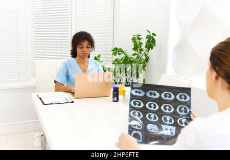 Focused worried multiethnic healthcare workers analyzing CT lung screening while working in medical clinic or hospital, medical team looking at x-ray Stock Photo