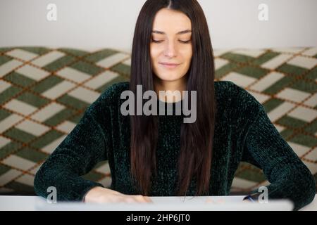 Beautiful white woman working on laptop computer. Adult student person studying online with smile. Young Caucasian female doing distant freelance work Stock Photo