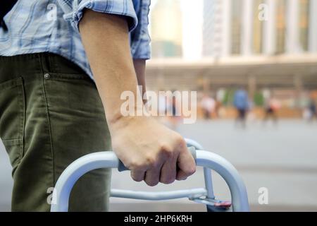 Close-up and selective focus right hand of man who used a walker tools for assist him to walk easily on blurred outdoor background Stock Photo