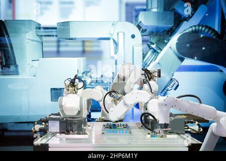 Industrial automation robotic teamwork working with circuit board on smart factory, on machine blue tone color background, industry 4.0 Stock Photo