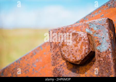 Old rusty bolts and steel nuts in the background a blurred sky and a field Stock Photo
