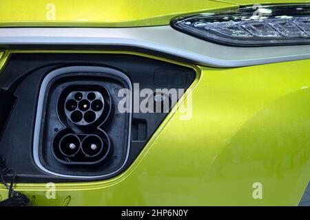 Close-up socket plug connecting on front of yellow smart vehicle (EV) for connect to electric charger machine for rechargeable battery Stock Photo