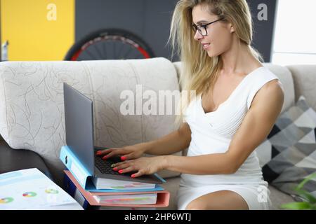 Beautiful young woman with tattoo works with laptop Stock Photo