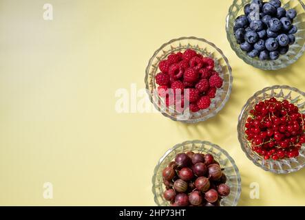 fresh summer berries in glass bowls on colored background Stock Photo