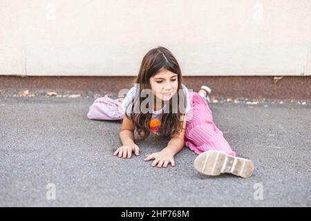 Little brunette girl casually doing split outdoors Stock Photo
