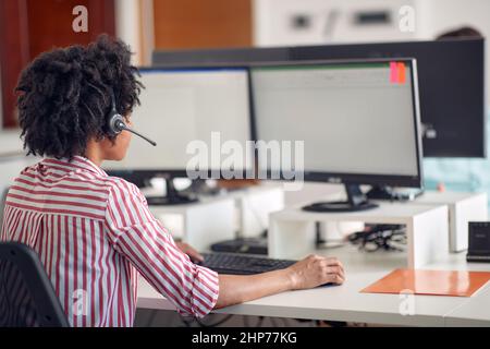 A young woman is focused on a work at the computer in a pleasant atmosphere in the office. Employees, job, office Stock Photo