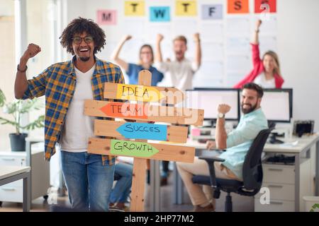 A young male office worker is promoting company slogans while posing for a photo in a pleasant atmosphere in the office. Employees, job, office Stock Photo
