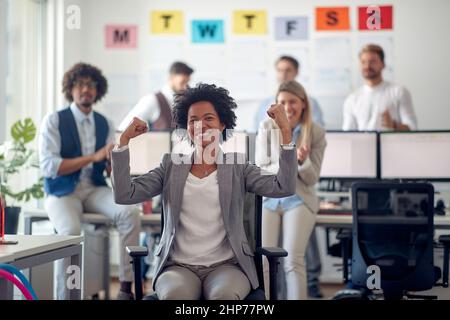 A young female employee enjoys posing for a photo with her colleagues in a pleasant atmosphere in the office. Employees, job, office Stock Photo