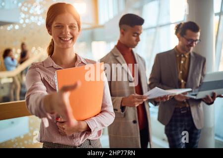 Close-up of a young business woman who stands in a pleasant atmosphere in the hallway with colleagues and wants to handshake. Business, people, compan Stock Photo